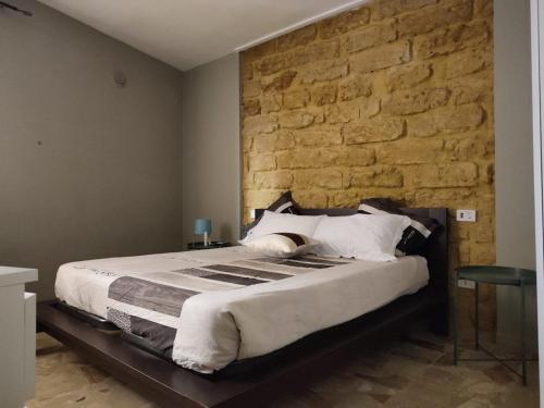 ein Schlafzimmer mit einem großen Bett mit Ziegelwand in der Unterkunft Le case di Grazia in Ioppolo Giancaxio