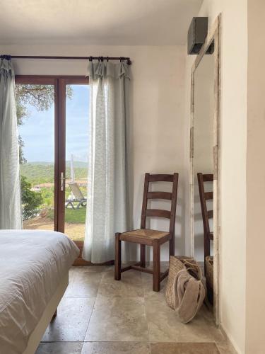 une chambre avec un lit, une chaise et une fenêtre dans l'établissement A Casa di Santa Giulia, à Porto-Vecchio