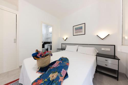 - une chambre avec un lit blanc et un panier dans l'établissement Bravissimo Vil·les Brusi A S'Agaró, à S'Agaro