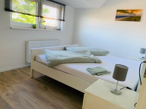 a white bedroom with a bed and a window at FEDDERSEN LIVING Kernsanierte Ferienwohnungen - Gemütlich - Netflix - Voll ausgestattet - zentral in Brunsbüttel