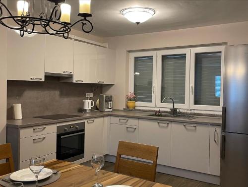 a kitchen with white cabinets and a table with wine glasses at Apartman Zaton in Zaton