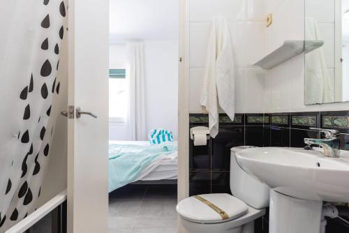 a bathroom with a sink and a toilet and a bed at Bravissimo Vil·les Brusi B S'Agaró in S'Agaro