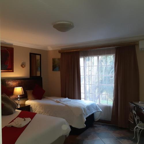 a hotel room with two beds and a window at Suikerbosrant Sleep and go in Pretoria