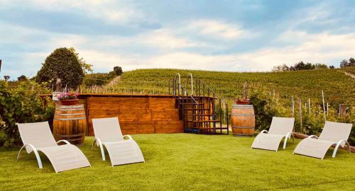 a group of chairs and wine barrels in a yard at Madama Langa Country House con piscina nelle vigne in Montelupo Albese