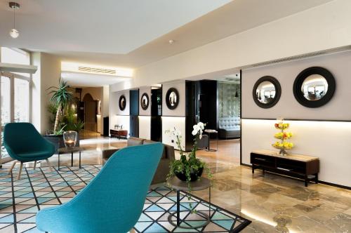a lobby with blue chairs and mirrors on the wall at Hotel Lombardia in Milan