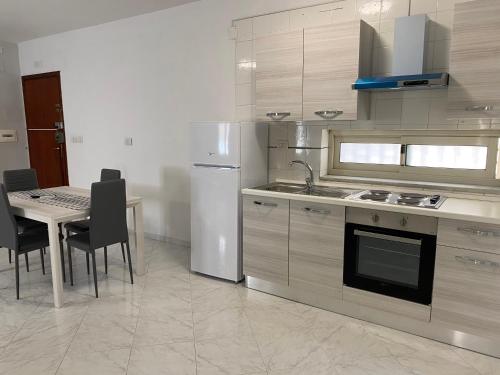 a kitchen with a table and a white refrigerator at Napoli Residence Casalnuovo in Casalnuovo di Napoli