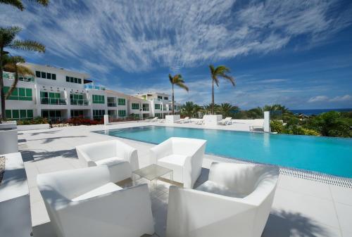 a resort pool with white chairs and a swimming pool at Piscadera Harbour Village in Willemstad