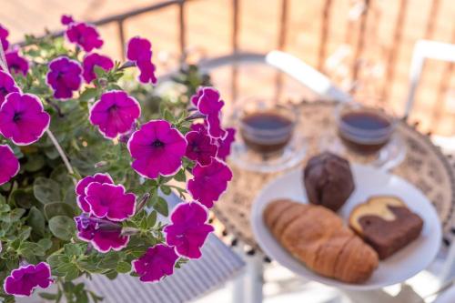 a table with a plate of pastries and purple flowers at Virvilis Apartments in Sivota