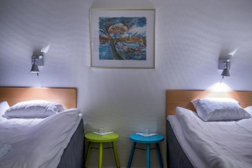 two beds in a room with two stools at Sunderby folkhögskola Hotell & Konferens in Luleå