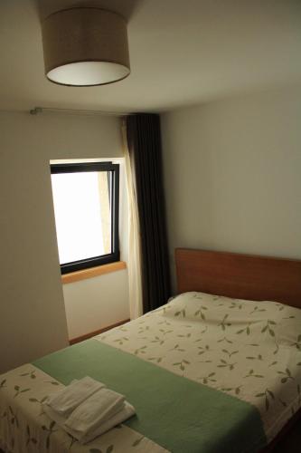 een slaapkamer met een bed met een groene deken en een raam bij Alojamento 4 Bicas in Seia