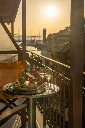 a table with a plate of food and wine glasses on a balcony at Virvilis Apartments in Sivota