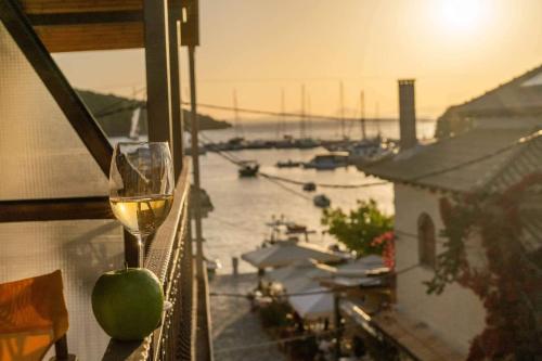 a glass of wine on a balcony with a view of a harbor at Virvilis Apartments in Sivota