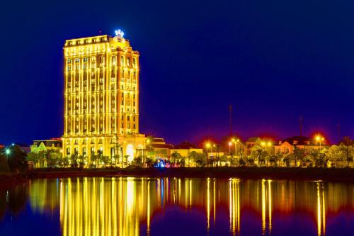 a large building at night next to a body of water at Rex Quang Binh Hotel in Dong Hoi
