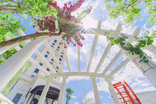 a white building with a tree with flowers on it at Rex Quang Binh Hotel in Dong Hoi