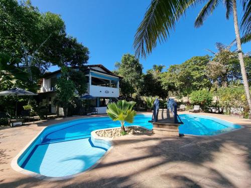 a swimming pool with two people standing next to a house at Solar das Orquídeas in Porto Seguro