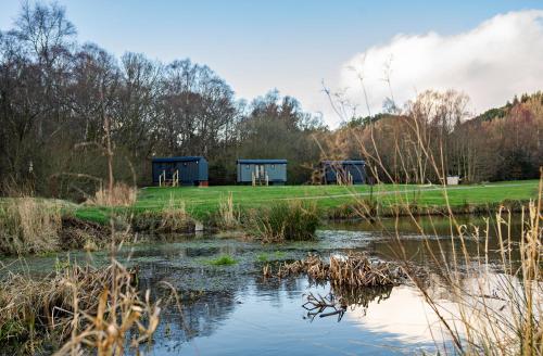 a view of two blue shelters in a park next to a pond at Loch Lomond Waterfront Luxury Lodges in Balmaha