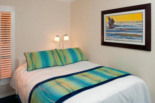 a bedroom with a bed with blue and green pillows at Casa Del Mar Beachfront Suites in Galveston