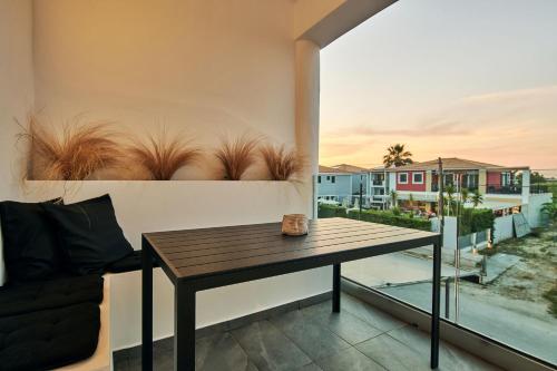 un balcone con un tavolo di legno e un divano di Amaroo Suites - 250m from the beach, by ZanteWize a Laganas