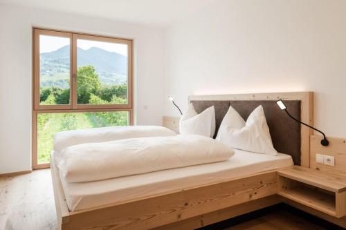 1 dormitorio con 1 cama blanca grande y ventana en Natur Suite Edelweisshof App Heidi, en Chiusa