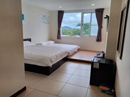 a bedroom with a bed and a large window at Julie's Garden in Hengchun South Gate