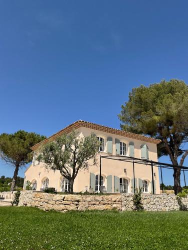 une grande maison avec un mur en pierre et des arbres dans l'établissement La Soleillade Aixoise, à Aix-en-Provence