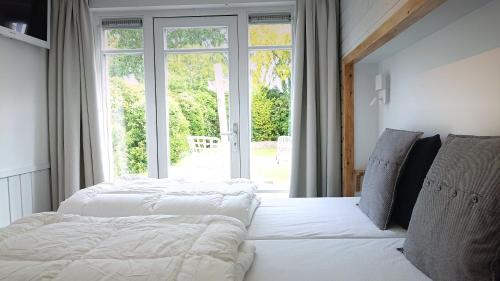 two beds in a room with a large window at huisje Zomervreugd in Burgh Haamstede