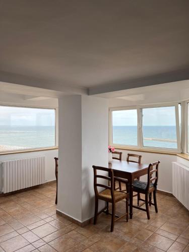 une salle à manger avec une table et des chaises et deux fenêtres dans l'établissement Panoramic Sea View Apartment, à Constanţa
