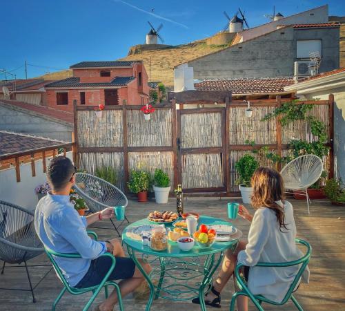 Un hombre y una mujer sentados en una mesa con comida. en Apartamentos Oncemolinos con desayuno, en Consuegra