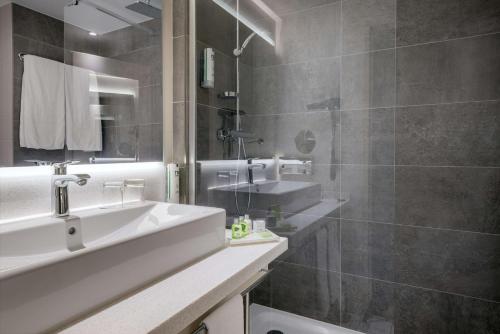 a bathroom with a sink, mirror and bath tub at NH Hamburg Altona in Hamburg