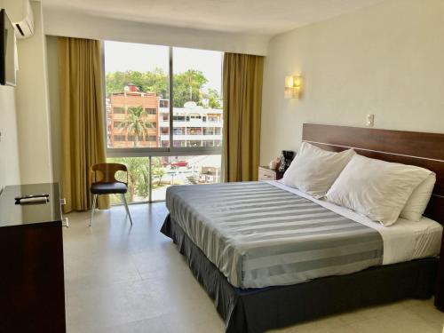 Cette chambre comprend un lit et une grande fenêtre. dans l'établissement May Palace Hotel , à Tuxpan