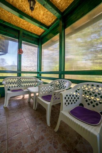 a room with white benches and tables and windows at Vikendica MRVICA in Bajina Bašta