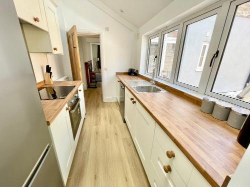 a kitchen with white cabinets and a wooden counter top at Rye Court Cottage and Annex Central Hemsley in Helmsley