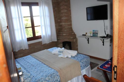 um quarto com uma cama, uma janela e uma televisão em Suite com terraço em Conceição da Ibitipoca