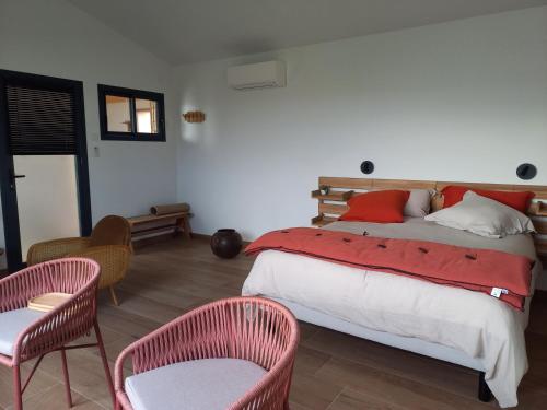 a bedroom with a bed with red pillows and two chairs at La lagune aux oiseaux in Palavas-les-Flots