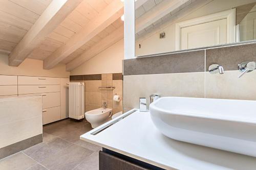 a bathroom with a white sink and a toilet at Il Golfo Attico Vista Lago in Toscolano Maderno