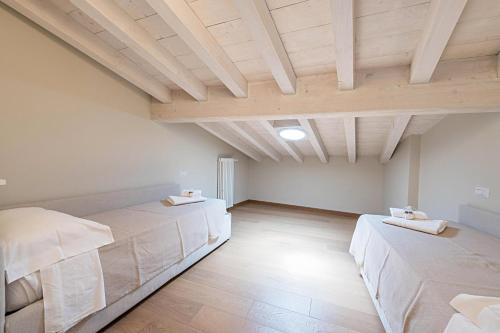 two beds in a large room with wooden ceilings at Il Golfo Attico Vista Lago in Toscolano Maderno