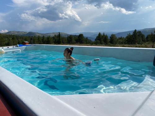 a woman swimming in a swimming pool with mountains in the background at Trollvang in Dovreskogen