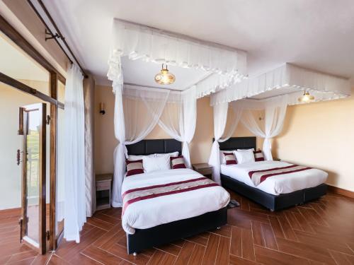 two beds in a bedroom with white curtains and wood floors at Olsupat Lodge in Nairobi