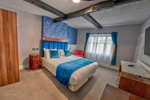 1 dormitorio con 1 cama grande y paredes azules en The Bridge Hotel, en Thrapston