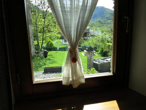 a window with a curtain and a view of a yard at Dialley prato Cir0014 in Aymavilles