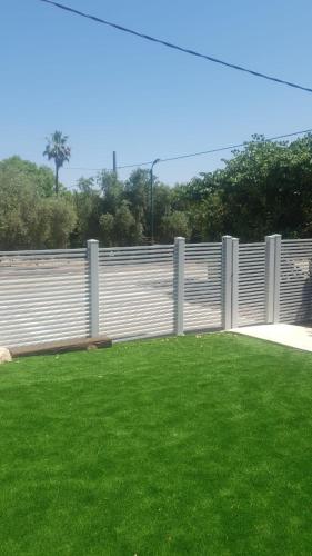 a white fence with green grass in front of it at אירוח פינת חן in Ramot Naftali