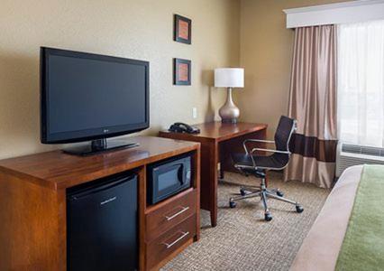 a hotel room with a television on a dresser with a desk at Comfort Inn Midland South I-20 in Midland