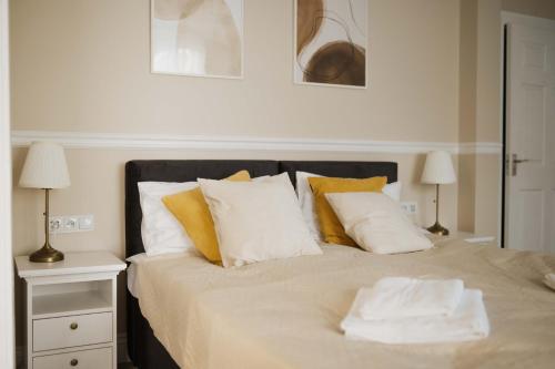 a bedroom with a bed with white and yellow pillows at Villa Adele in Polanica-Zdrój