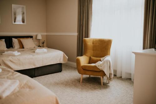 a hotel room with a chair and a bed at Villa Adele in Polanica-Zdrój