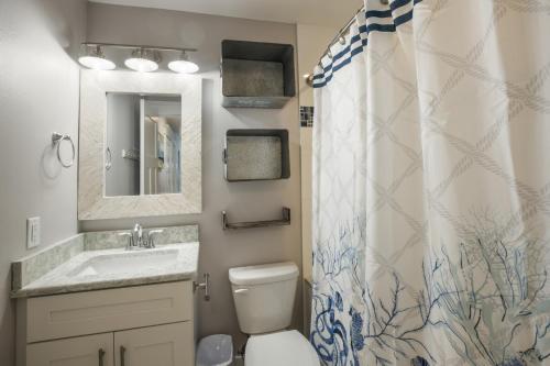 a bathroom with a sink and a toilet and a shower curtain at Royal Palm: Pool, 2 Blocks to Beach, Close to Dining & Shopping by Anna Maria Life Vacation Rentals in Holmes Beach
