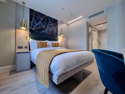 - une chambre avec un grand lit et une chaise bleue dans l'établissement NOX Edgware Road, à Londres
