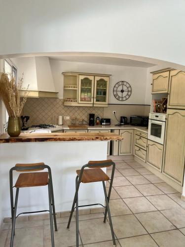 - une cuisine avec un comptoir et 2 chaises dans l'établissement Océan à 10 mn, maison avec piscine, bar et babyfoot, à Saint-Paul-en-Born