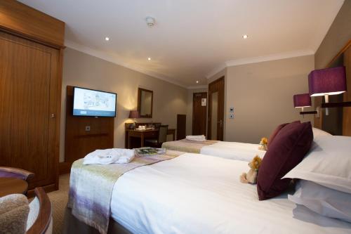 a hotel room with two beds and a flat screen tv at The Stanneylands in Wilmslow