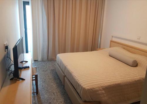 ein Hotelzimmer mit einem Bett und einem TV in der Unterkunft E.J. Pyrgos Bay Hotel in Kato Pyrgos