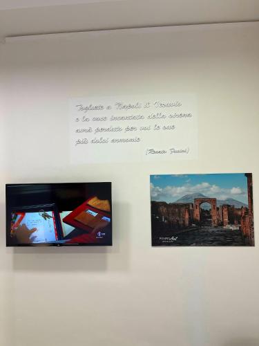 a sign with two pictures and a tv on a wall at Pompei Art in Scafati